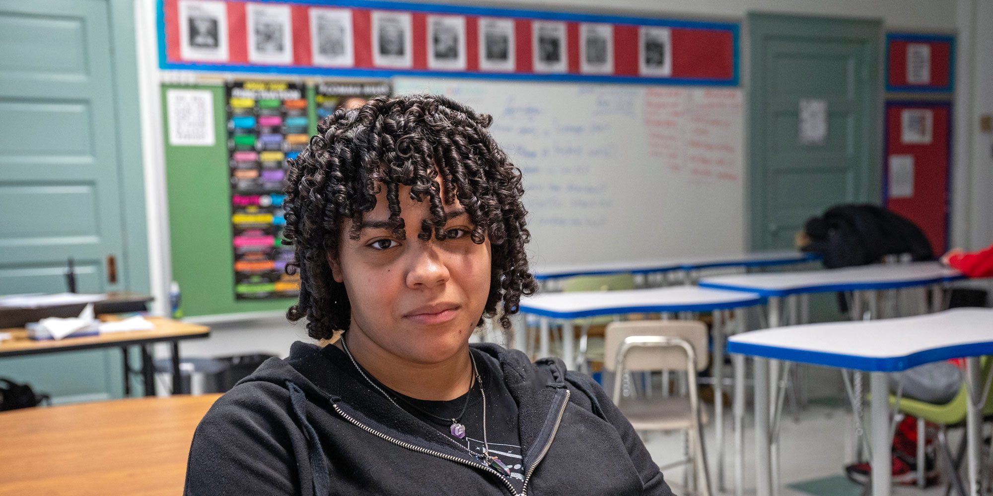 Student with curly hair seated in a classroom.
